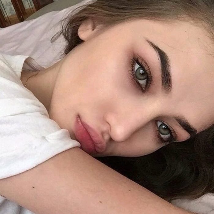 Chica recostada en una cama mirando hacia el frente para mostrar sus ojos verdes