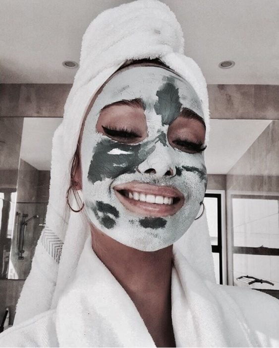 Chica usando mascarilla de menta para refrescar la piel mientras seca su cabello con una toalla sobre la cabeza