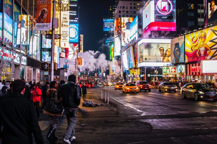 Ciudad de Nueva York llena de gente, a mitad de la noche, con las luces de los negocios encendidas