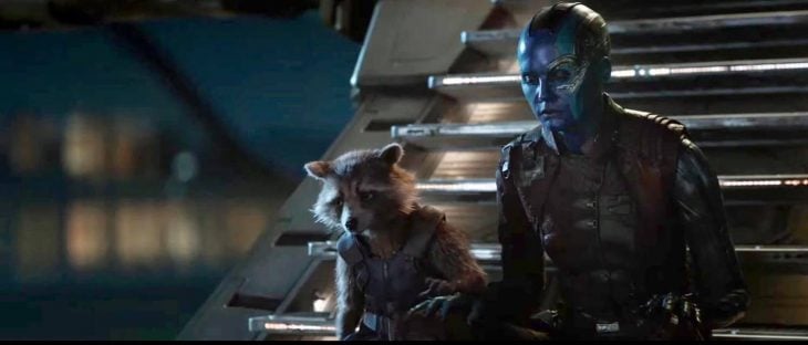 Personajes de la película Avengers: Endgame sentados en unas escaleras color plateado, tomados de la mano, Nebula, Rocket Racoon 