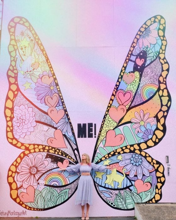 La cantante Taylor Swift frente a un mural de una mariposa