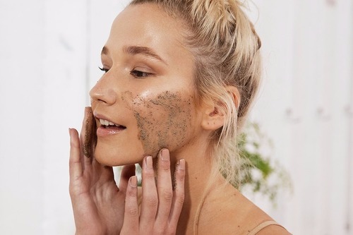 Chica dentro de un baño, mirándose frente al espejo para limpiar su cara 