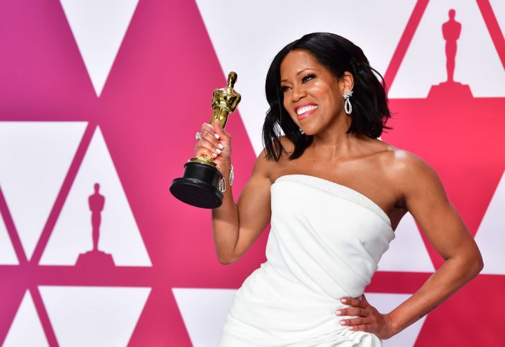 Peinados y looks que los Óscar 2019, Regina King con cabello corte bob ondulado arriba de los hombros y vestido blanco, sosteniendo un premio Óscar