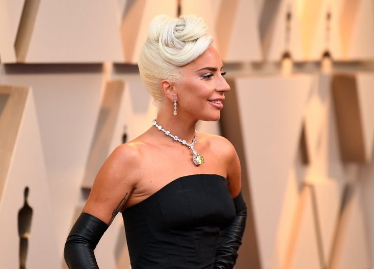 Peinados y looks que los Óscar 2019, Lady Gaga con peinado recogido estilo vintage romántico, vestido y guantes negros