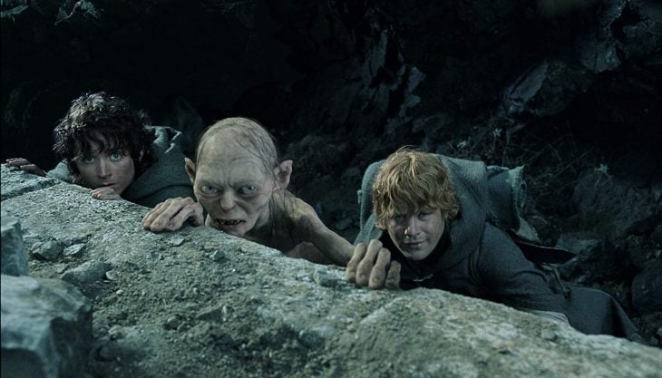 Elijah Wood y Sean Astin vestidos como hobbits escalando una montaña rocosa en la película El Señor de los Anillos: el retorno del Rey
