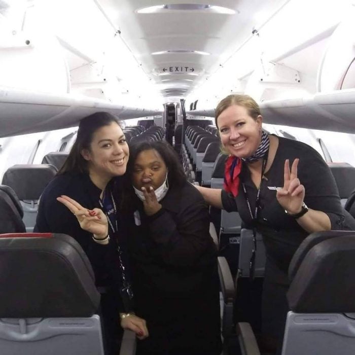 Shantell Pooser, azafatas dentro de un avión de American Airlines, haciendo señal de amor y paz, sonriendo para una fotografía del recuerdo
