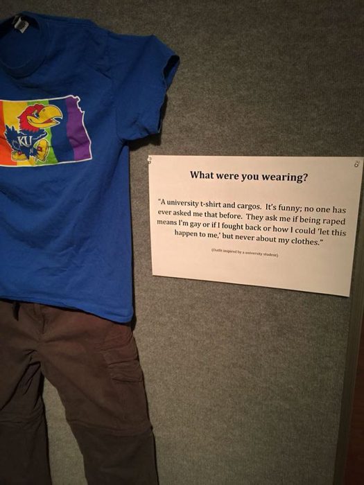 Camisa azul de una universidad y pantalones color café expuestos en una galería de arte 