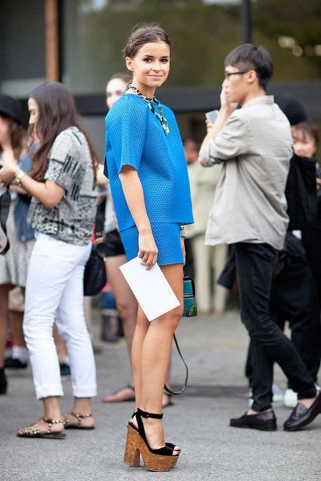 Girl standing posing for a photo while wearing a blue suit and swedish brown with black 