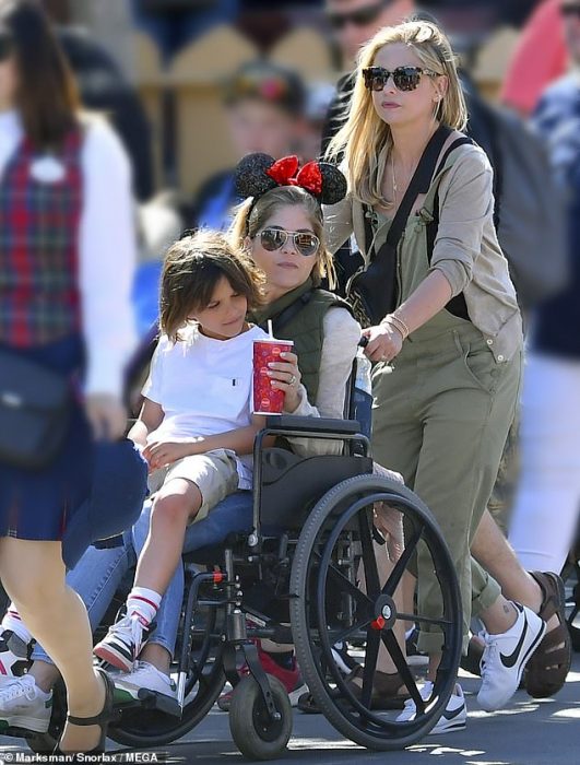 La actriz Sarah Michelle Gellar empujando la silla de ruedas de la actriz Selma Blair en Disneylandia mientras carga a su hijo