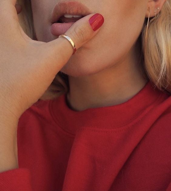 Chica tocando sus labio con el dedo pulgar de su mano izquierda el cual tiene un anillo dorado