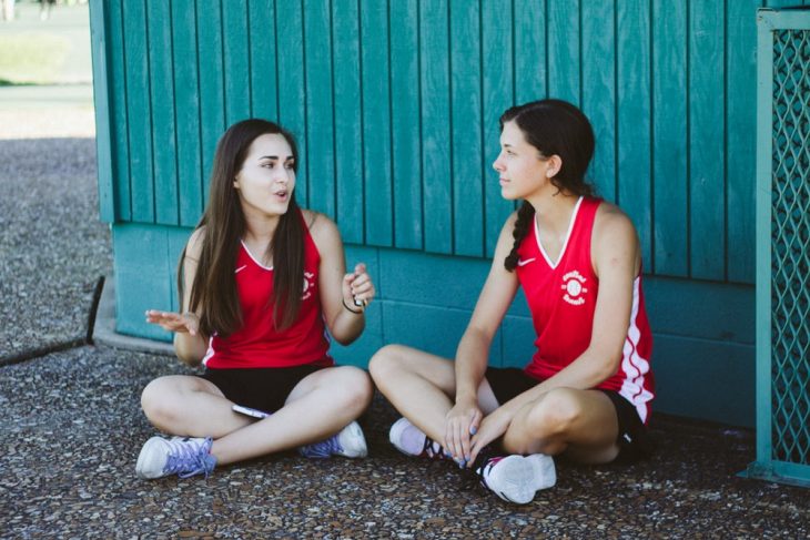 Tipo de amiga Cáncer, par de amigas sentadas en el asfalto platicando sobre un partido de fútbol 