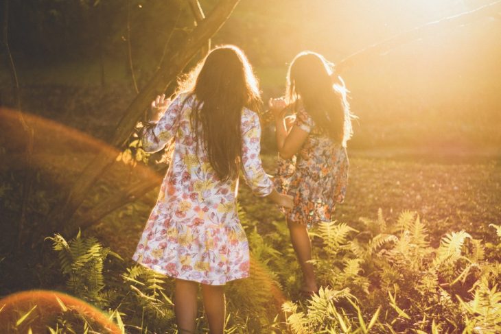 Tipo de amiga Capricornio, chicas con vestidos floreados corriendo por el campo a manera de juego mientras se divierten con sus amigas 