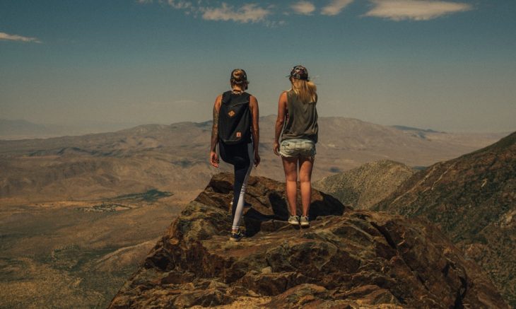 Tipo de amiga Geminis, amigas volteadas de espaladas, paradas sobre la cima de una montaña admirando el paisaje