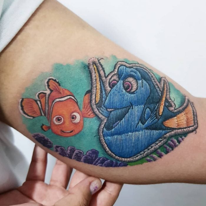 Tatuaje bordado de Buscando a Nemo, Dori, en el brazo, de tatuador brasileño Eduardo "Duda" Lozano