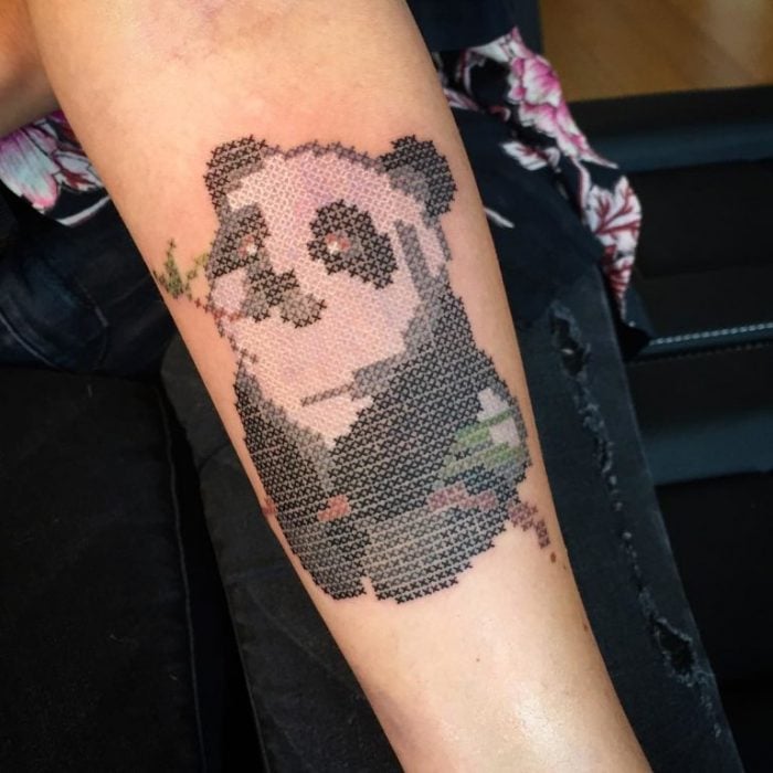 Tatuaje de panda comiendo bambú, con efecto bordado en punto de cruz