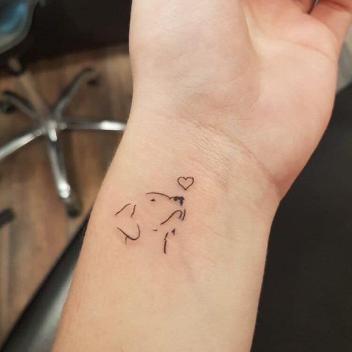 Tatuaje pequeño de un cachorro con un corazón