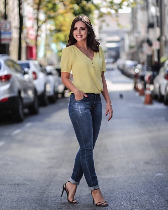 Chica caminando por la calle con blusa verde y jeans de mezclilla