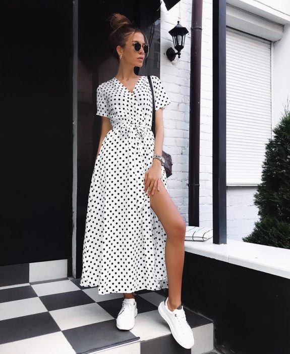 Chica modelando un wrap dress con tenis blanco y gafas oscuras