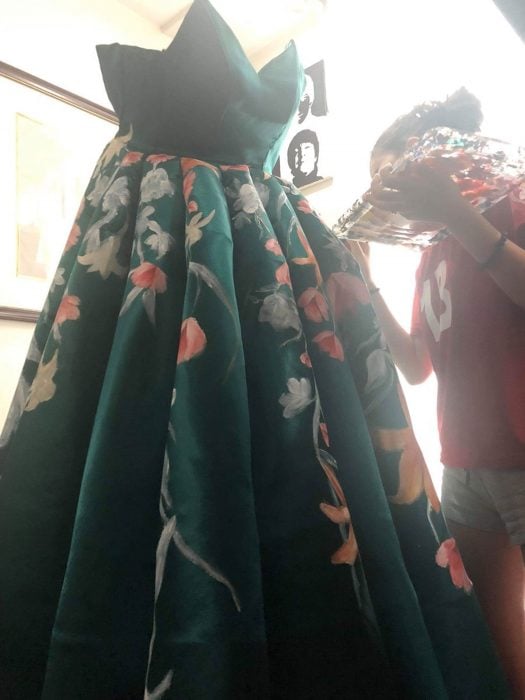 Estidiante filipina Ciara Gan confeccionó su propio vestido de graduación ampón largo, color verde esmeralda con flores tigre anaranjadas y amarillas, chica pintando a mano su vestido de fiesta