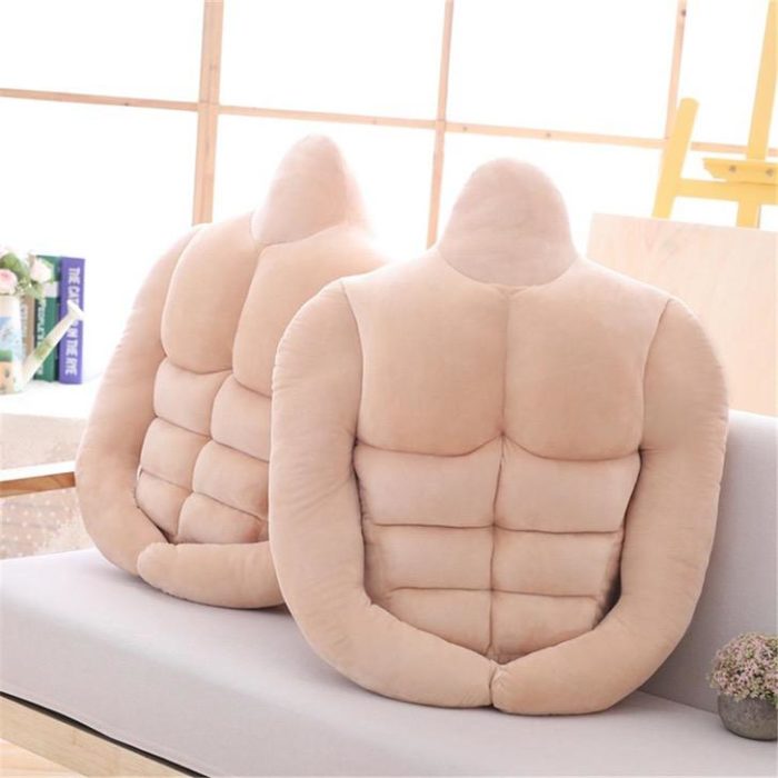 Par de almohadas colocadas en un sofá. Tienen forma de hombre con sixpack y brazos 