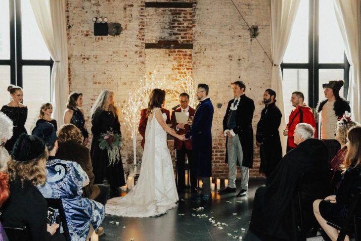 Novios se casan en boda inspirada en Harry Potter; esposa con vestido blanco y esposo con traje azul con invitados