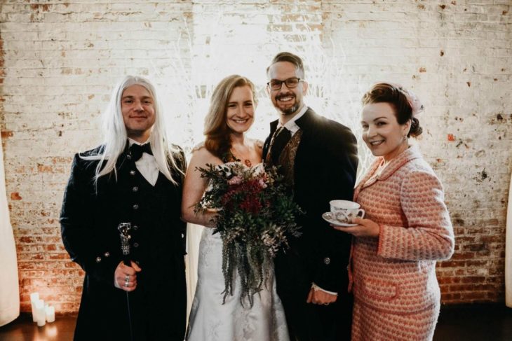 Novios se casan en boda inspirada en Harry Potter; novia con vestido blanco, novio con traje azul, invitados disfrazados de Lucius Malfoy y Dolores Umbridge