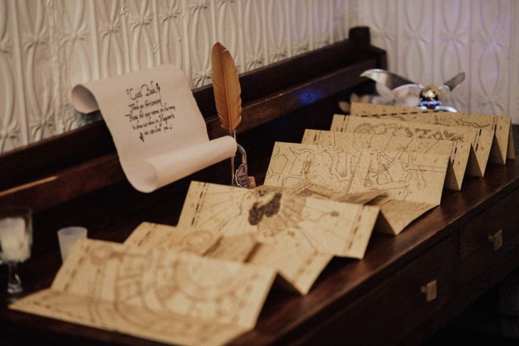 Novios se casan en boda inspirada en Harry Potter; libro de firmas que parece el mapa del merodeador con una pluma para escribir