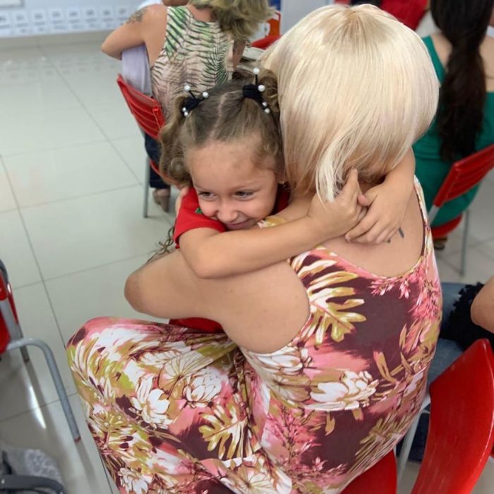 Daniel Correa, papá viudo de una niña, se disfraza de mujer para asistir al festival del Día de las Madres de la escuela, con barba rosa, peluca rubia y vestido floreado; papá abrazando a su hija