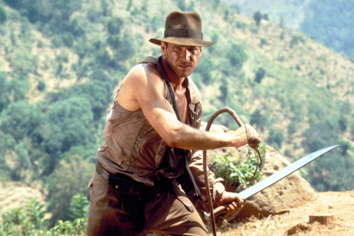 Movie scene Indiana Jones with Harrison Ford holding a whip and a sword ready to fight