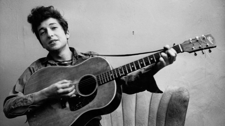 Bob Dylan tocando la guitarra sentado en un sofá, Rolling Thunder Revue: A Bob Dylan Story By Martin Scorsese 