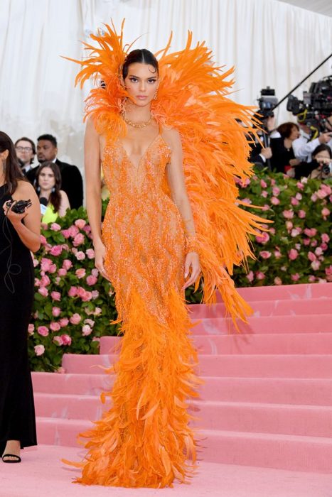 Kendall Jenner usando un vestido de color naranja entallado y cubierto de plumas durante la Gala MET