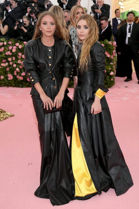 Mary-Kate y Ashley Olsen usando vestidos similares de cuero negro con aplicaciones en amarillo durante la Gala del MET