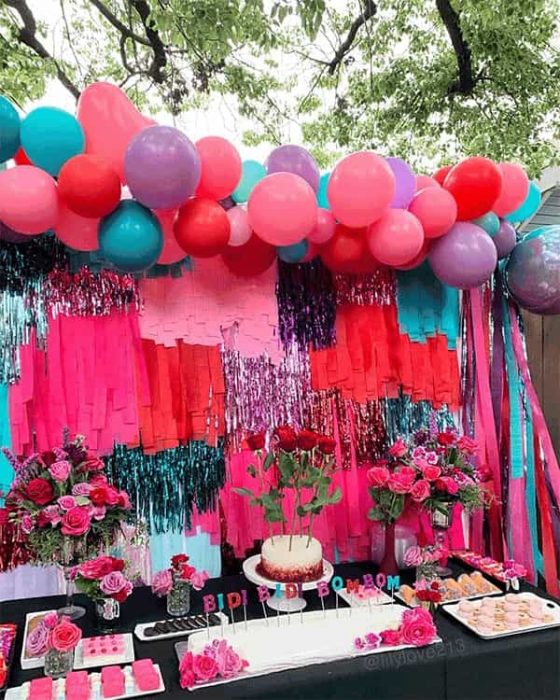 mesa de postres decorada con globos, rosas y velas que dicen bidi bidi bom bom 