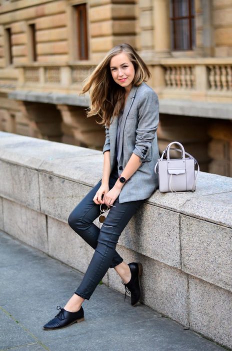 Chica recargada en una barda luciendo su outfit y sus zapatos estilo oxford 