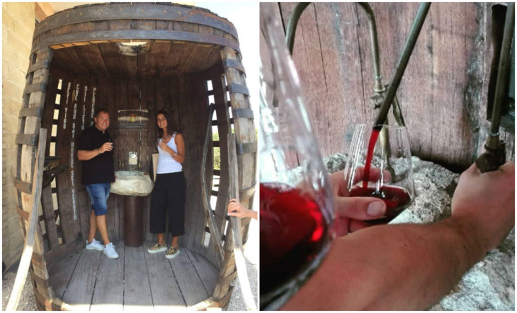 Hombre y mujer dentro de un barril gigante bebiendo vino tinto