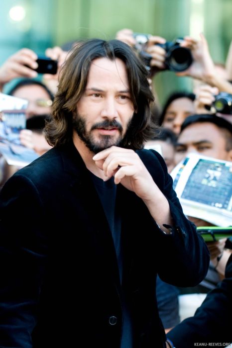 Actor Keanu Reeves, hombre con cabello largo y barba, traje de vestir negro