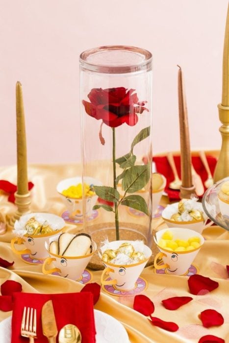 Ideas para quinceañera estilo La Bella y la Bestia de Disney; Chip, la taza, como dulcero; flor dentro de cristal como centro de mesa