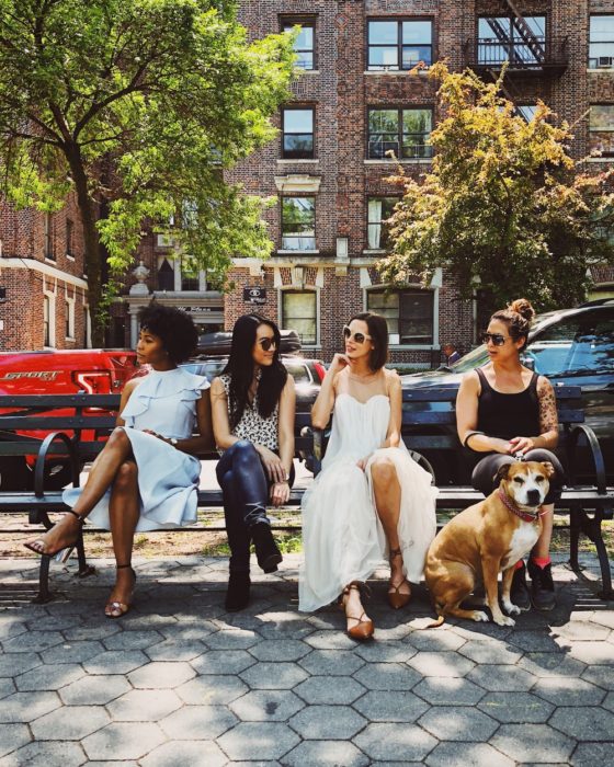 Grupo de cuatro mujeres sentadas en la banca de un parque charlando