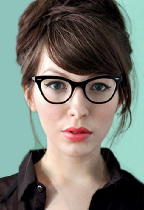 Chica posando para una foto mientras enseña sus pequeños lentes estilo vintage de color negro
