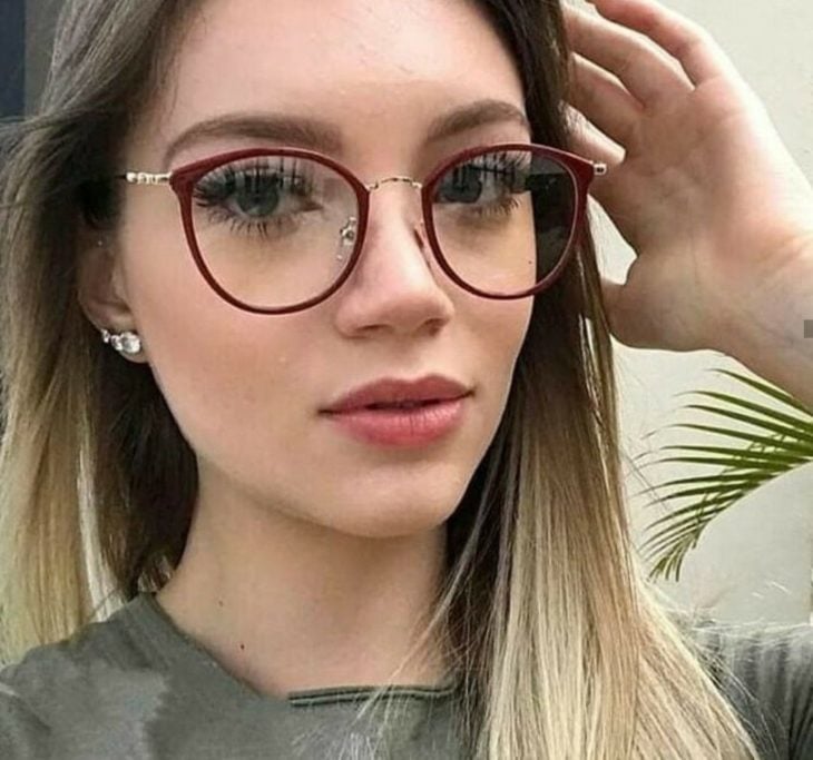 Chica posando para una foto mientras muestra sus gafas redondas de color morado