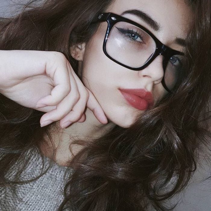 Chica posando para una selfie en la que muestra sus lentes de color negro 