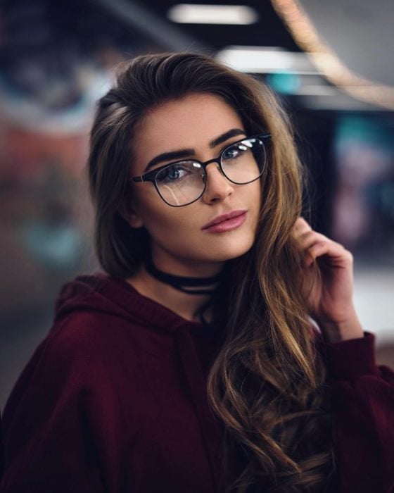 Chica posando para una foto en la que muestra sus gafas de color negro 