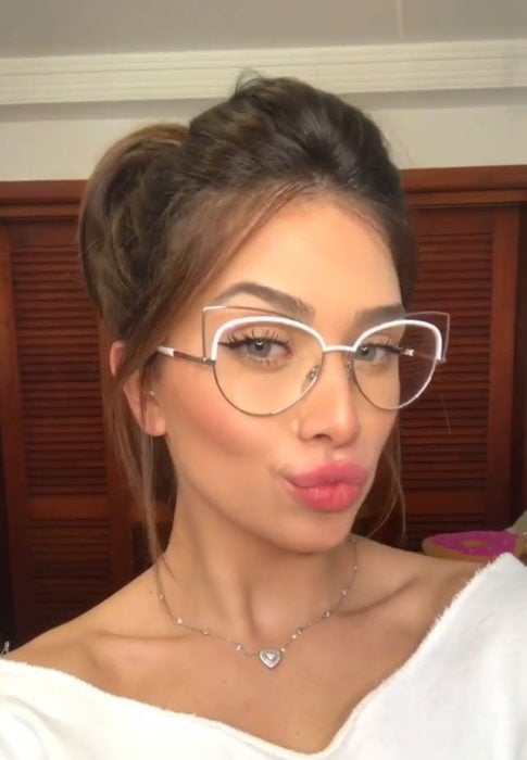 Chica tomandose una selfie y mostrando su gafas de color blanco con transparencias 