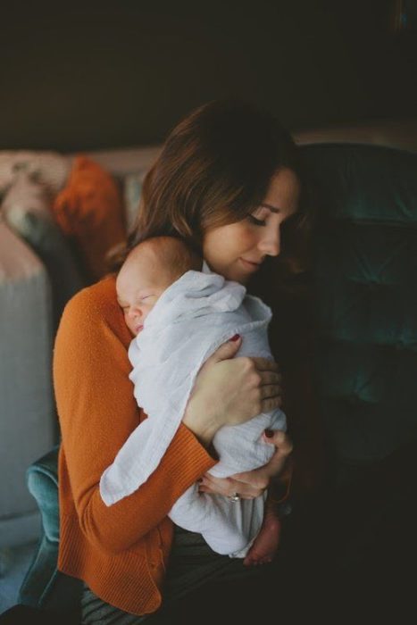 Mamá joven cargando a su bebé de meses