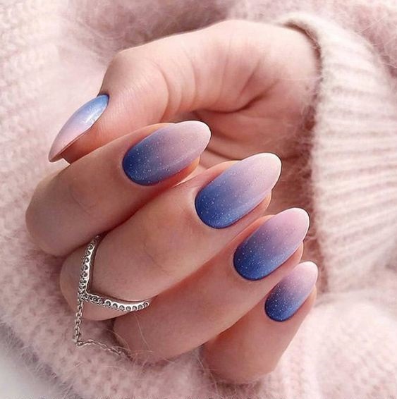 Mano de mujer con uñas ovaladas en color azul pastel