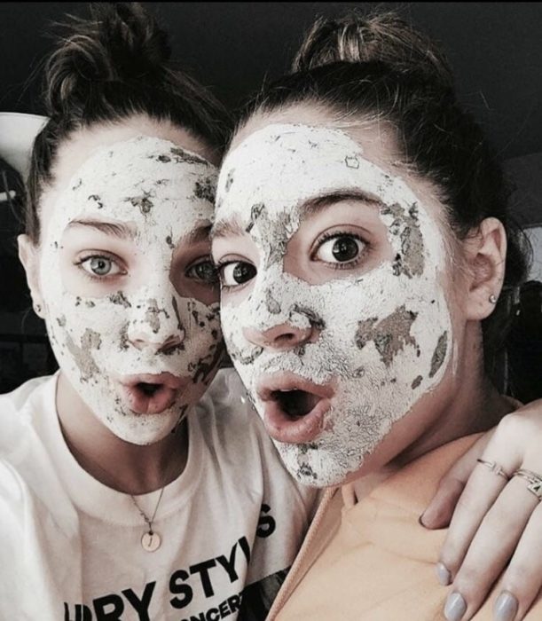 Amigas usando mascarilla faciales para combatir imperfecciones, abrazadas