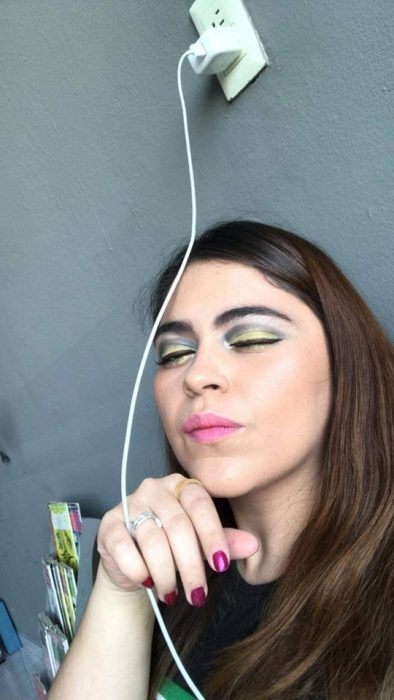 Chica ayuda a su mejor amiga a maquillarse vía Whatsapp, selfie de mujer con maquillaje mal hecho, sombras amarilla y negra, labial rosa y uñas magenta