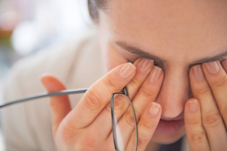 Mujer joven con los dedos sobre los ojos cerrados