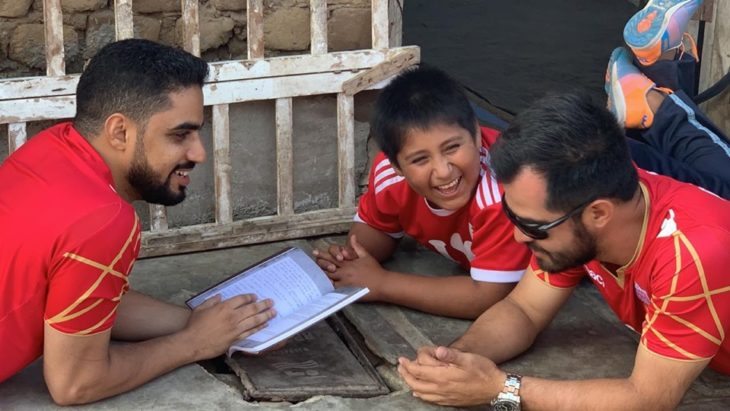 Empresario árabe, Yaqoob Yusuf Ahmed Mubarak jugando en el suelo con Victor Martín Angulo Córdoba, niño peruano que hace la tarea bajo un poste de luz