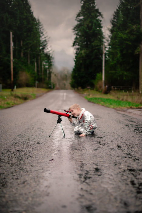 Cosas graciosas que dicen los niños; niño vestido de astronauta mirando a través de un telescopio rojo